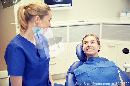 Image of happy female dentist with patient girl at clinic