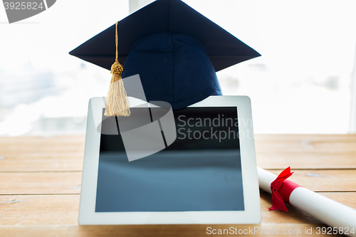 Image of close up of tablet pc with mortarboard and diploma