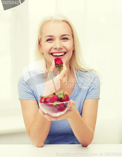 Image of happy woman eating strawberry at home