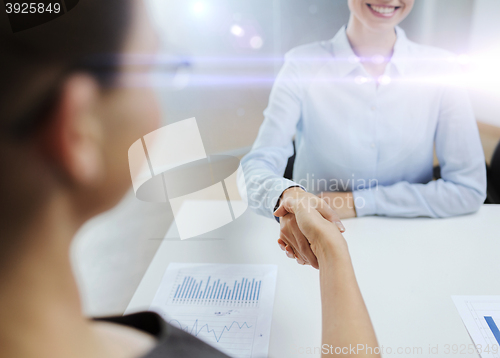 Image of two smiling businesswoman shaking hands in office