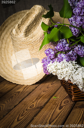 Image of Still-life with a bouquet of lilacs and a straw hat, close-up