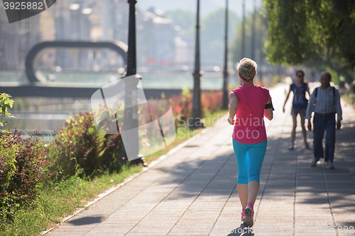 Image of sporty woman running  on sidewalk