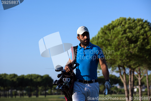 Image of golfer  walking and carrying bag