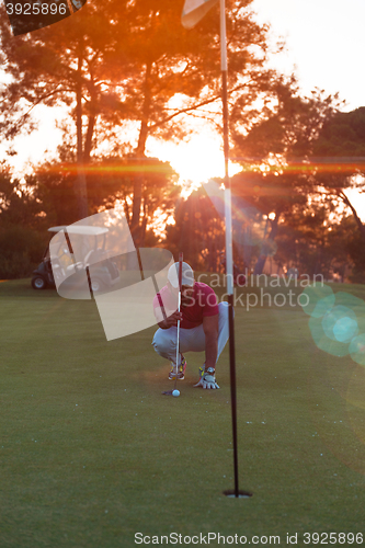 Image of golf player aiming perfect  shot on beautiful sunset