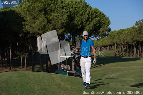 Image of golfer  walking and carrying golf  bag