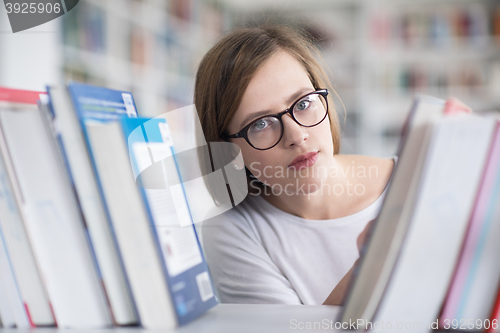 Image of portrait of famale student selecting book to read in library