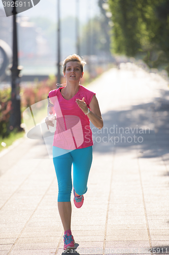 Image of sporty woman running  on sidewalk