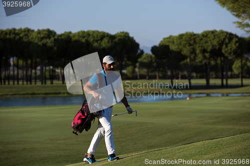 Image of golfer  walking and carrying bag