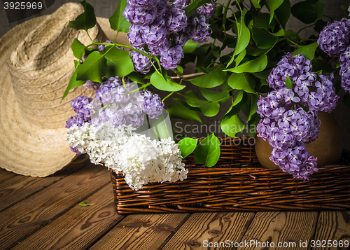 Image of Still-life with a bouquet of lilacs and a straw hat, close-up