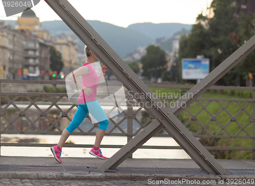 Image of sporty woman running  on sidewalk