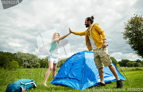 Image of happy couple setting up tent outdoors