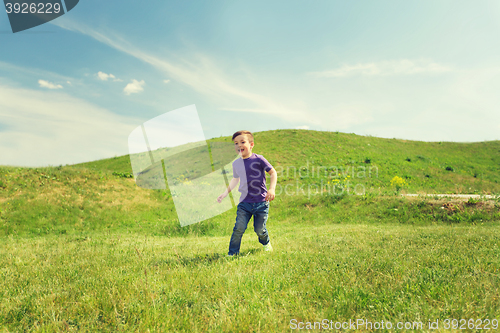 Image of happy little boy running on green field outdoors