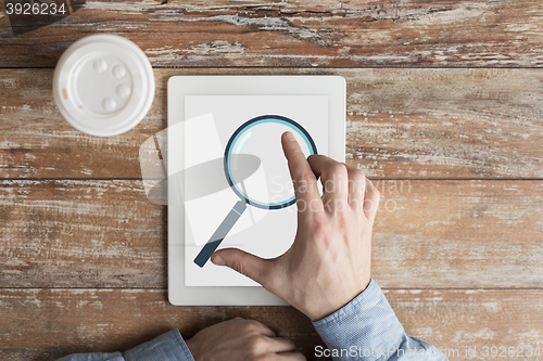 Image of close up of male hands with magnifier on tablet pc