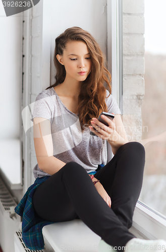 Image of sad pretty teenage girl with smartphone texting