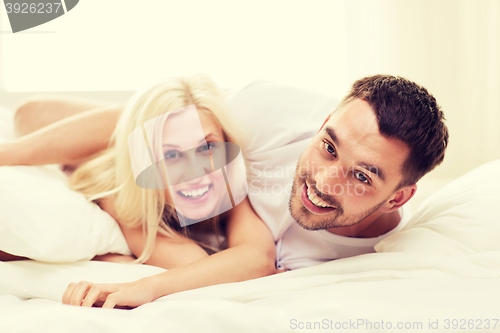 Image of happy couple lying in bed at home