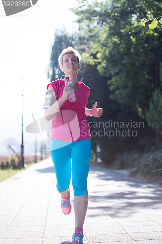 Image of sporty woman running  on sidewalk