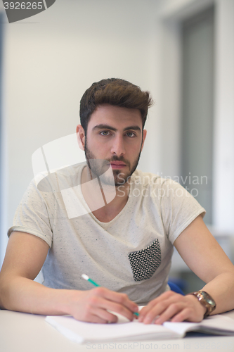 Image of male student taking notes in classroom