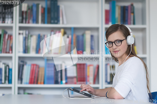 Image of female student study in library, using tablet and searching for 