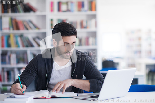 Image of student in school library using laptop for research