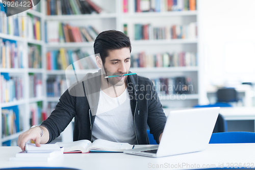 Image of student in school library using laptop for research