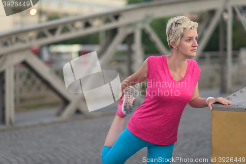 Image of blonde woman  stretching before morning jogging