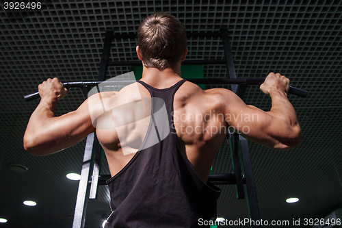 Image of Strong muscular man doing pull ups on bar