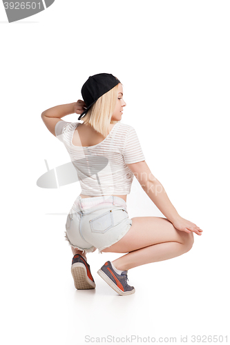 Image of Female model in tshirt and shorts squating on haunches isolated