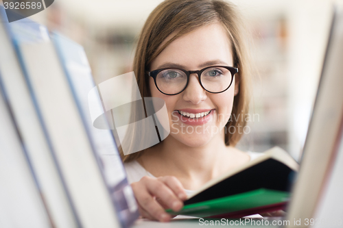 Image of portrait of famale student selecting book to read in library