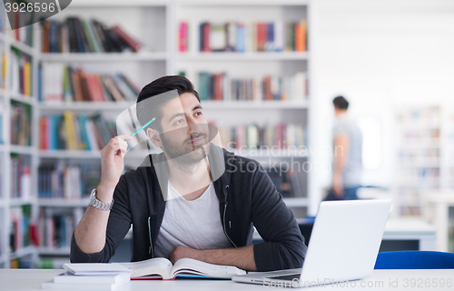 Image of student in school library using laptop for research