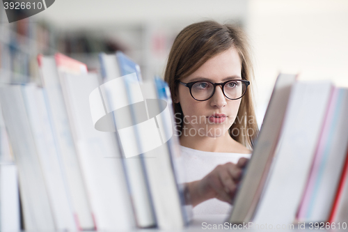 Image of portrait of famale student selecting book to read in library