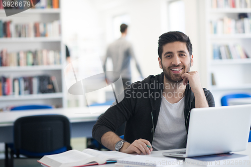 Image of student in school library using laptop for research