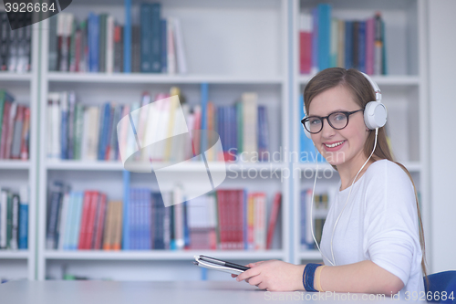 Image of female student study in library, using tablet and searching for 