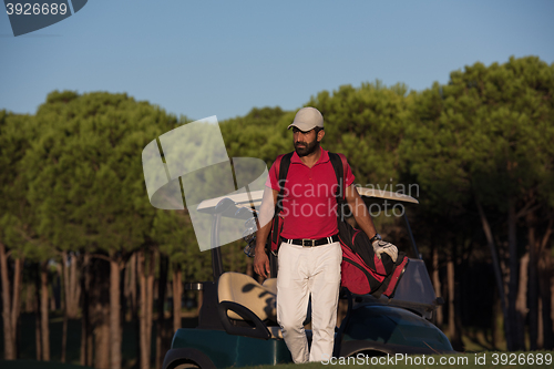 Image of golfer  walking and carrying golf  bag