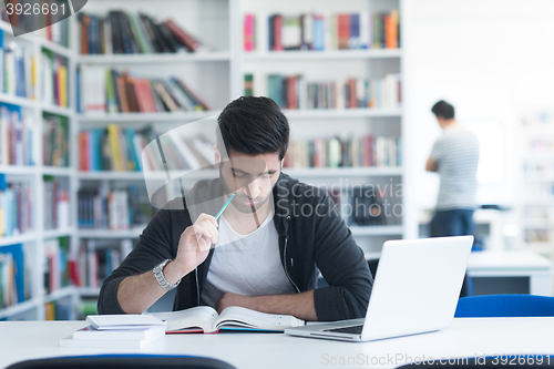 Image of student in school library using laptop for research