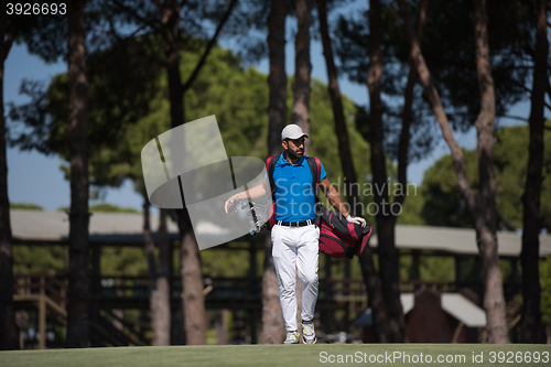 Image of golf player walking and carrying bag