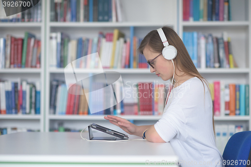 Image of female student study in library, using tablet and searching for 