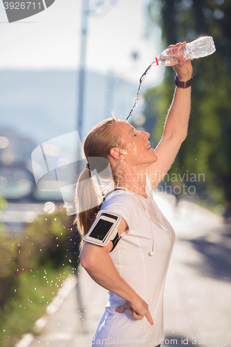 Image of woman drinking  water after  jogging