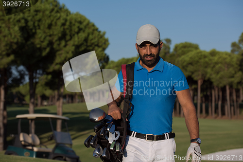 Image of golfer  walking and carrying golf  bag