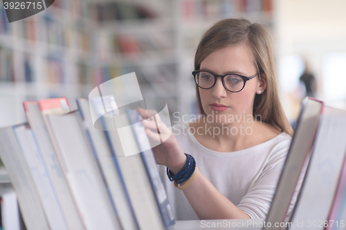 Image of portrait of famale student selecting book to read in library