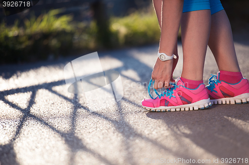 Image of Closeup of woman tying running shoe