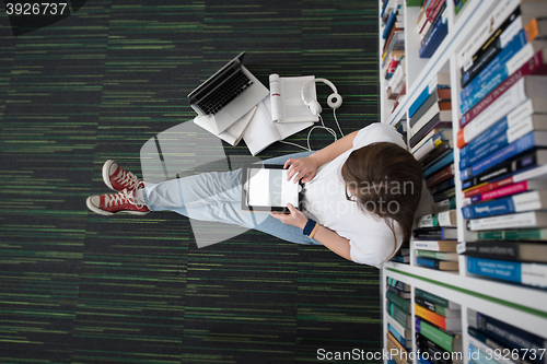 Image of female student study in library, using tablet and searching for 