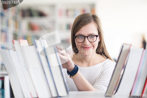 Image of portrait of famale student selecting book to read in library