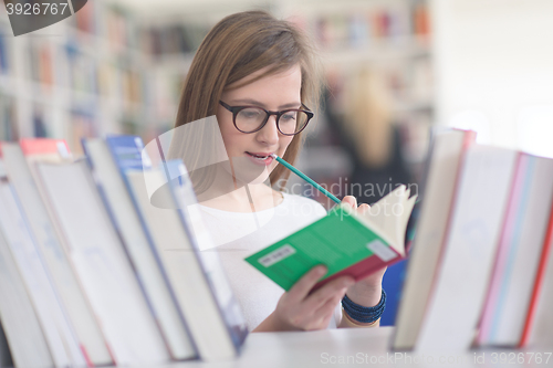 Image of portrait of famale student selecting book to read in library