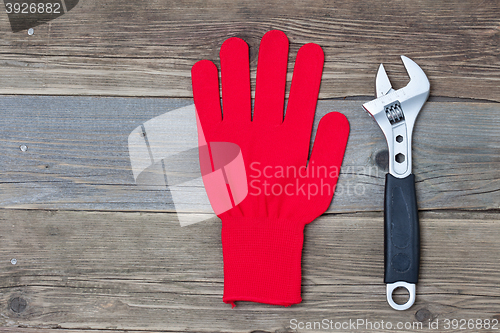 Image of Red protective glove and an adjustable pipe wrench