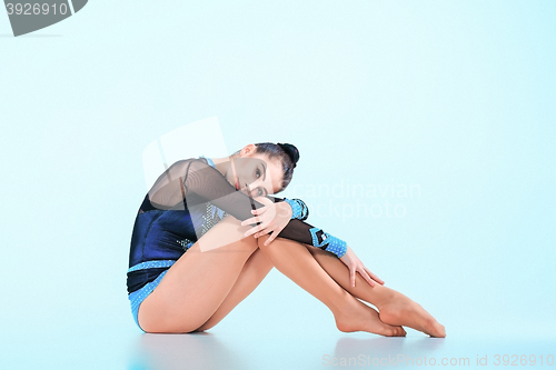Image of The girl sitting after gymnastics dance on a blue background
