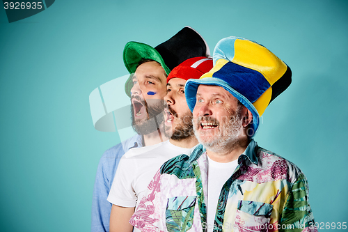 Image of The three football fans singing the national anthem over blue