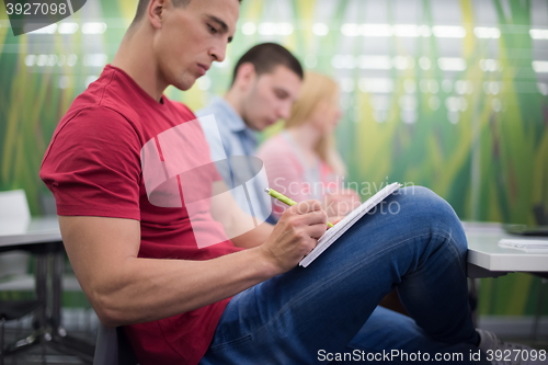 Image of male student taking notes in classroom