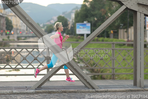 Image of sporty woman running  on sidewalk