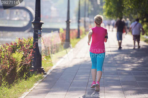 Image of sporty woman running  on sidewalk