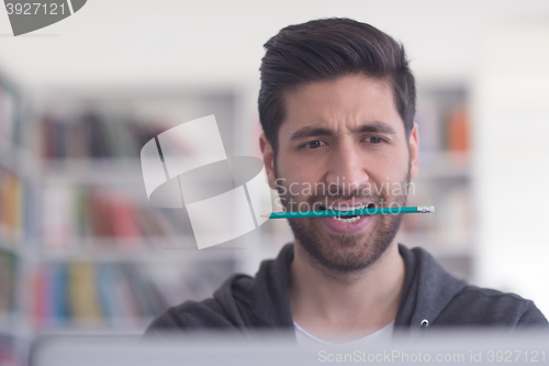 Image of student in school library using laptop for research